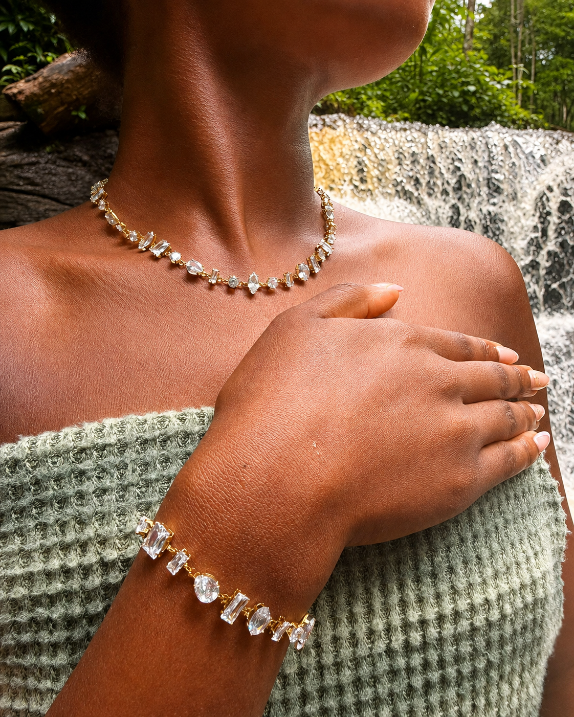 Collier et bracelet dorés KEORA portés devant une cascade